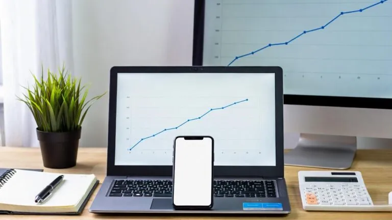IA para pequenos negócios: mesa de trabalho organizada com notebook, celular e gráficos de crescimento exibidos nas telas, representando como a inteligência artificial ajuda empreendedores a automatizar tarefas, analisar dados e aumentar resultados de forma simples e acessível.