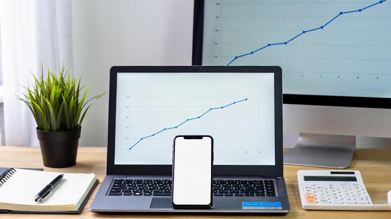 IA para pequenos negócios: mesa de trabalho organizada com notebook, celular e gráficos de crescimento exibidos nas telas, representando como a inteligência artificial ajuda empreendedores a automatizar tarefas, analisar dados e aumentar resultados de forma simples e acessível.