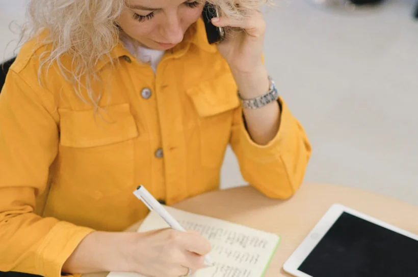 Profissional conversando por telefone enquanto registra compromissos em agenda