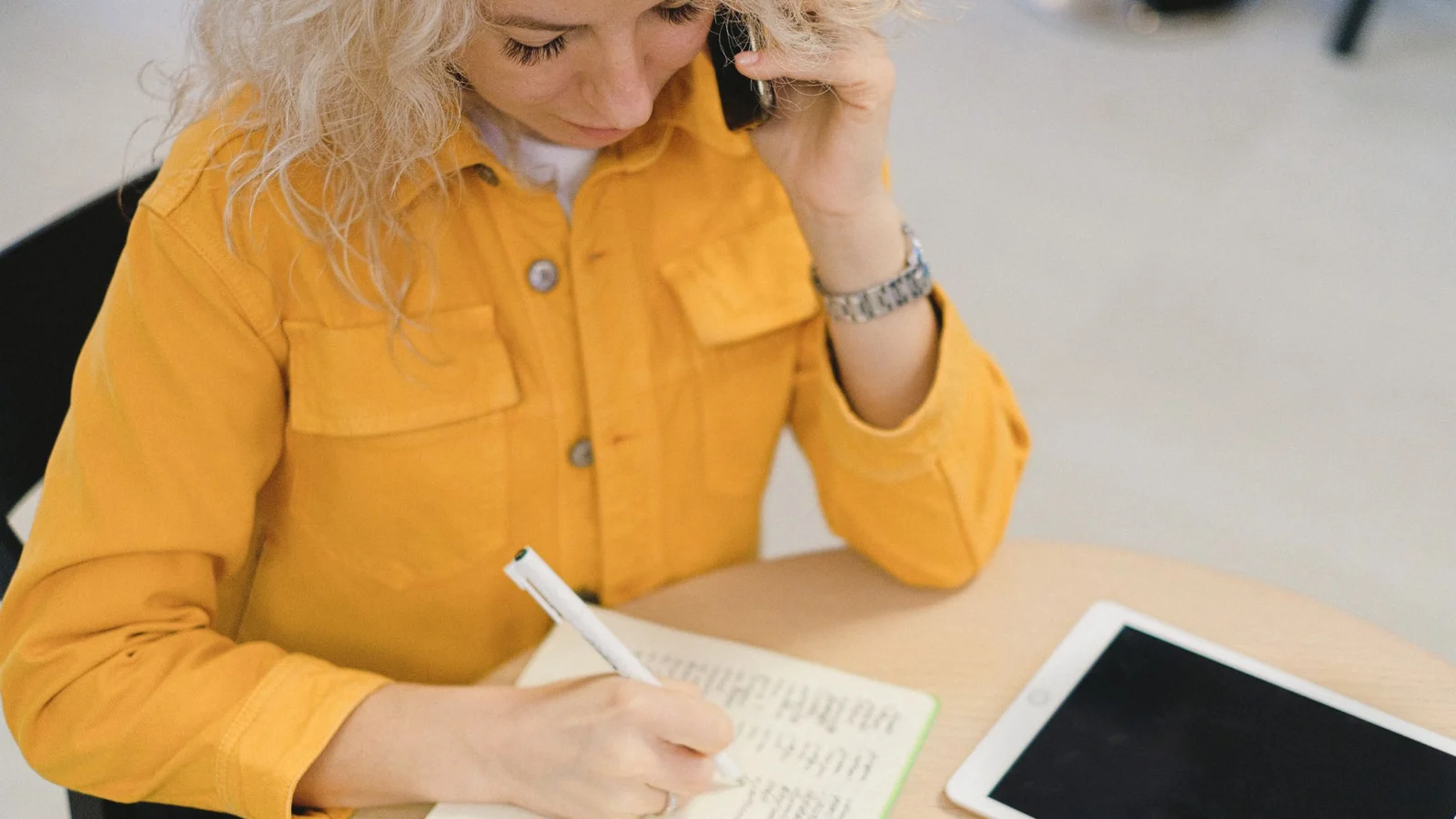 Profissional conversando por telefone enquanto registra compromissos em agenda