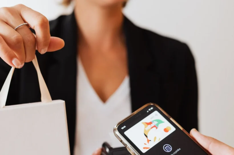 Prevenção a fraudes em pagamentos: cliente usando celular e máquina de pagamento em comércio