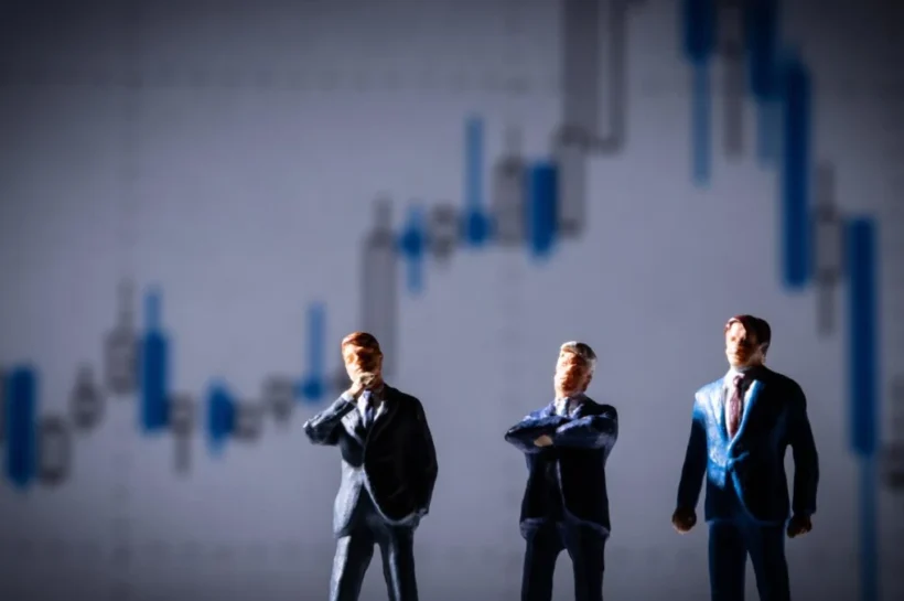 Profissionais em ambiente empresarial diante de gráficos econômicos